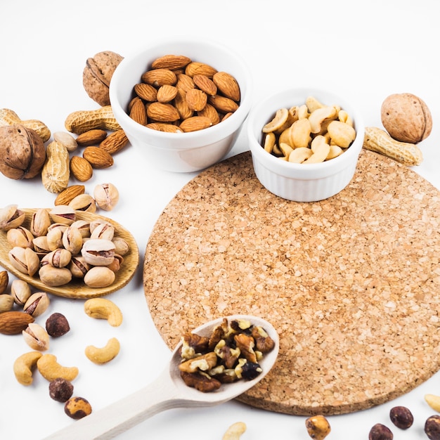 Healthy dried fruits bowl and spoon with cork coaster on white background