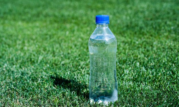 健康的な飲み物地球環境保全プラスチックごみは、緑の草のスポーツとフィットネスで新鮮で清潔な感じののどが渇いた純粋な天然飲料ミネラルビタミンウォーターボトルをリサイクルする必要があります