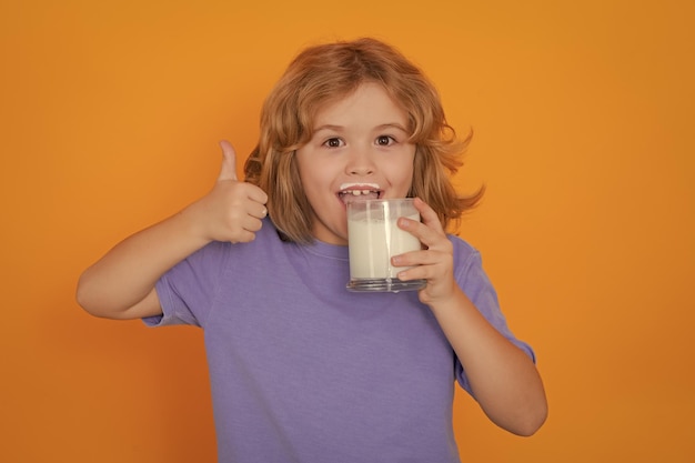 Healthy drink with calcium and protein for kids Funny blonde child drinking milk isolated on yellow Little boy with milk mustache hold glass of milk