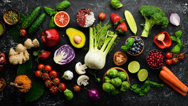 Healthy eating concept: vegetables and fruits on black stone background. Top view. Free space for your text.