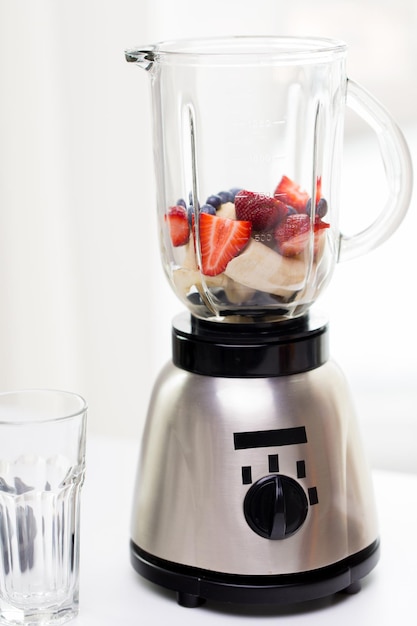 Photo healthy eating, cooking, kitchen appliances and technology concept - close up of blender shaker with fruits and berries
