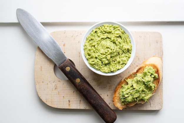 Healthy eating cream made from avocado on toast with a bowl of guacamole