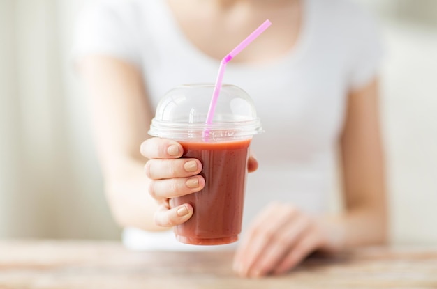 healthy eating, diet and people concept - close up of woman holding plastic cup with juice or smoothie