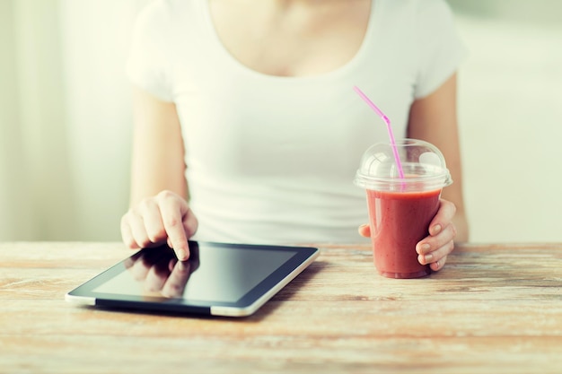 здоровое питание, диета, технологии и концепция людей - крупный план женских рук с планшетным компьютером и чашкой смузи, сидящих за столом