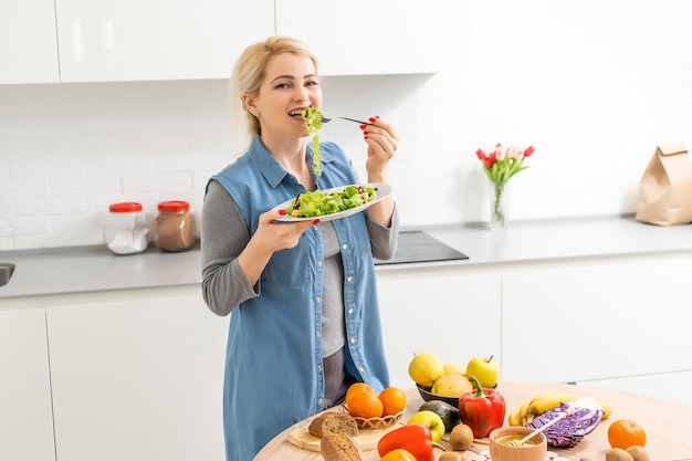 healthy eating, dieting and people concept - close up of young woman eating vegetable salad at home.