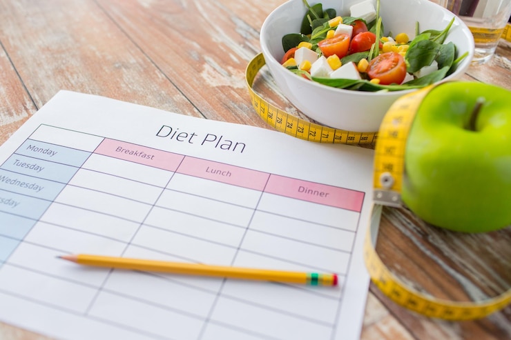 Photo healthy eating, dieting, slimming and weigh loss concept - close up of diet plan paper green apple, measuring tape and salad