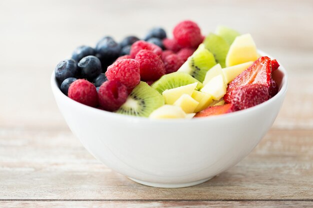 healthy eating, dieting, vegetarian food and people concept - close up of fruits and berries in bowl on table