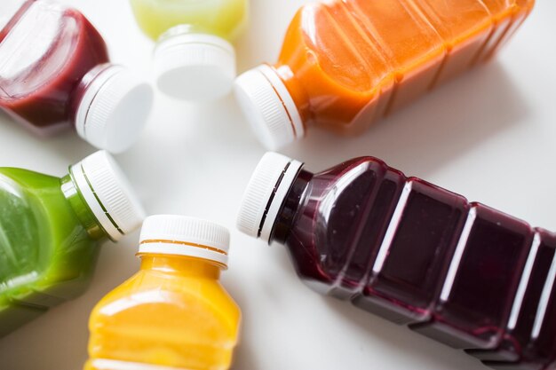 Photo healthy eating, drinks, diet and detox concept - close up of plastic bottles with different fruit or vegetable juices on white