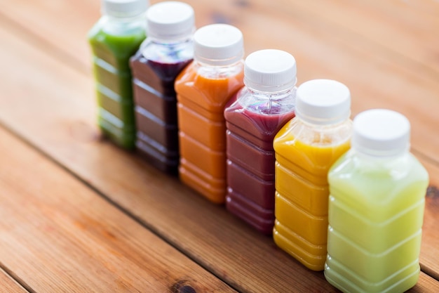 Healthy eating, drinks, dieting and packaging concept - plastic bottles with different fruit or vegetable juices on wooden table