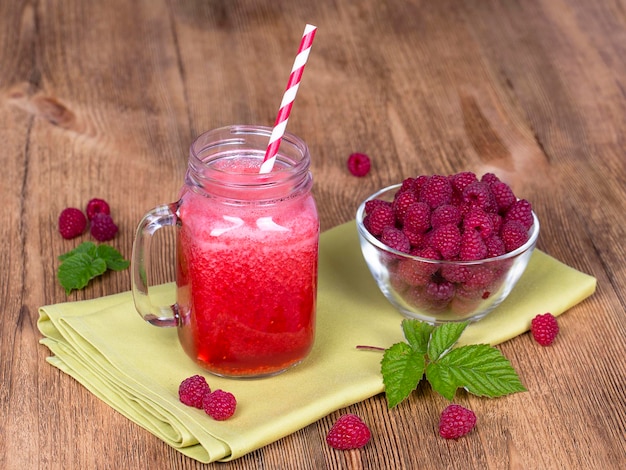 Healthy eating food dieting and vegetarian concept glass mug of juice smoothie shake from raspberries and raw raspberry on wooden background close up