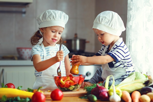 Healthy eating Happy children prepares and eats vegetable salad in kitchen