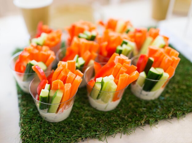 Healthy eating, vegetarian food, diet and culinary concept - close up of vegetable snacks on table decorated with artificial grass