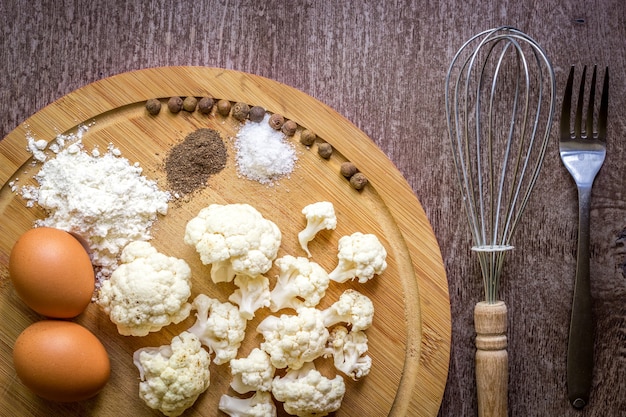 Healthy eating, vegetarian food. Raw cauliflower prepared for frying in a frying pan with spices in olive oil. Top view. Wooden background. Copy space. Still life. Flat lay