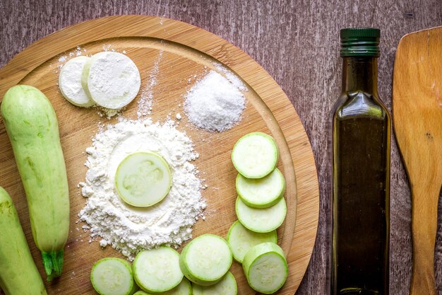 Healthy eating, vegetarian food. Raw zucchini prepared for frying in a frying pan with spices in olive oil. Top view. Wooden background. Copy space. Still life. Flat lay