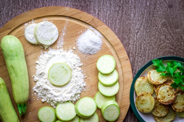 Healthy eating, vegetarian food. Raw zucchini prepared for frying in a frying pan with spices in olive oil. Top view. Wooden background. Copy space. Still life. Flat lay