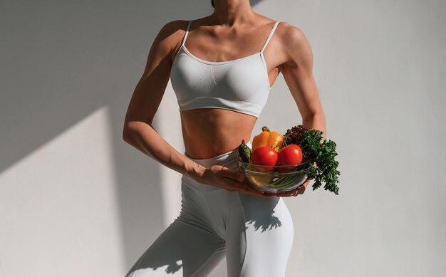 healthy eating With fruits Young caucasian woman with slim body shape is indoors in the studio