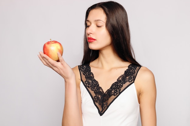 Healthy eating. Woman biting red apple with perfect teeth over grey background