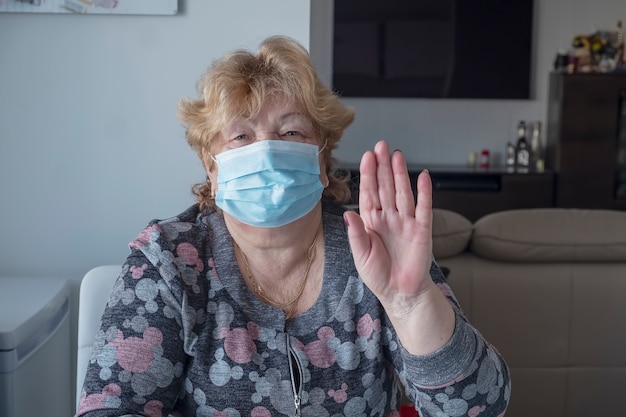 제스처 중지를 표시하는 파란색 의료 보호 마스크에 건강 한 노인 여성. 코로나 바이러스 발생