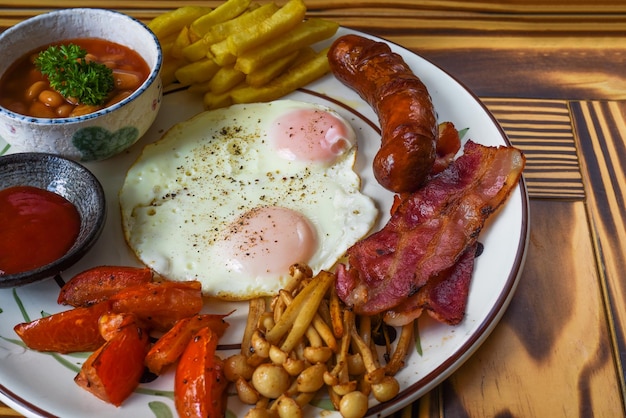 Здоровый английский завтрак с жареными яйцами, беконом, картофелем фри, фасолью и помидорами крупным планом