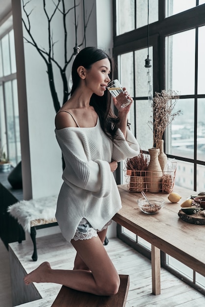 Healthy equals happy. Attractive young woman drinking water with lemon and smiling 