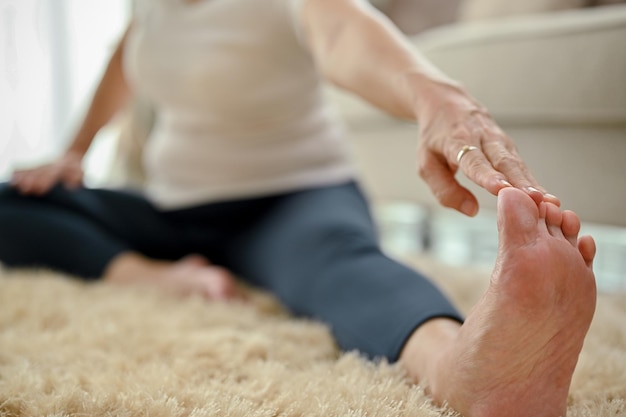 Healthy fit Asianaged woman stretching leg and arm practicing yoga selective focus