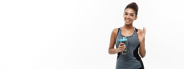 Healthy and fitness concept beautiful african american girl in sport clothes holding water bottle a