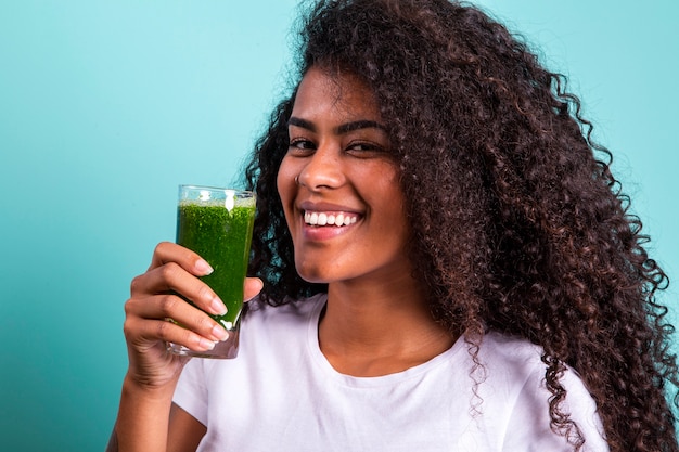 Healthy and Fitness concept - Beautiful American African lady in fitness cloth drinking healthy vegetable drink.