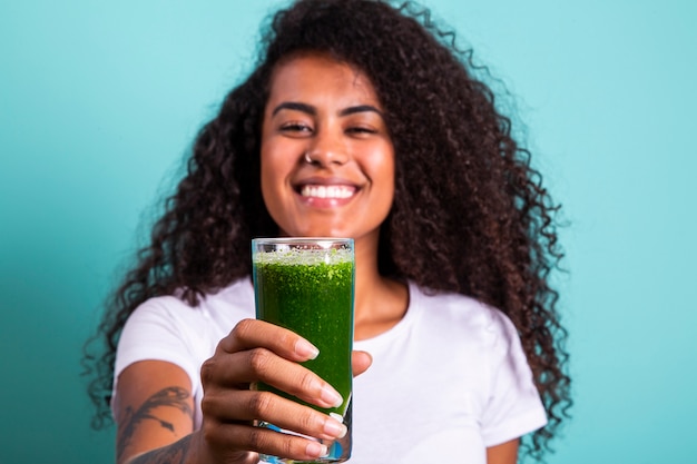 Healthy and Fitness concept - Beautiful American African lady in fitness cloth drinking healthy vegetable drink. 