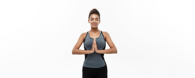 Healthy and Fitness concept Beautiful American African lady in fitness clothing doing yoga and meditation Isolated on white background