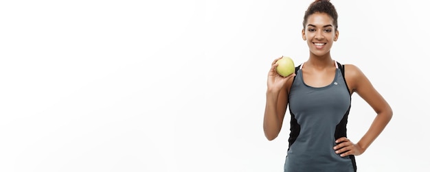Healthy and fitness concept beautiful american african lady in grey fitness clothes holding green a