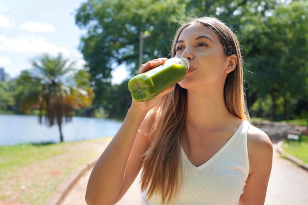 写真 都市公園でキウイミントケールを入れたグリーンスムージーデトックスジュースを飲む健康フィットネスの女の子