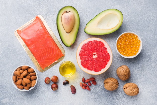 健康食品抗酸化製品：魚とアボカド、ナッツと魚油、グレーのコンクリート背景にグレープフルーツ。
