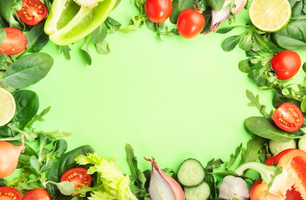 Healthy food background with various green herbs and vegetables Ingredients for cooking salad Vegetarian and vegan food concept Top view green frame with copy space