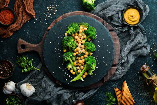 Healthy food Broiled broccoli chickpeas and sesame on a black stone plate Top view Free space for text