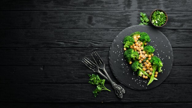 Healthy food Broiled broccoli chickpeas and sesame on a black stone plate Top view Free space for text