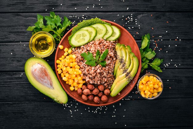 Healthy food Buckwheat avocado cucumber corn and hazelnut On a wooden background Top view Free space for your text