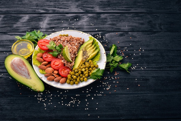 Healthy food. Buckwheat, cherry tomatoes, avocados, almonds and green peas. On a wooden background. Top view. Free space for your text.