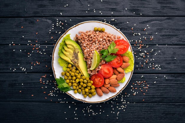 Healthy food Buckwheat cherry tomatoes avocados almonds and green peas On a wooden background Top view Free space for your text