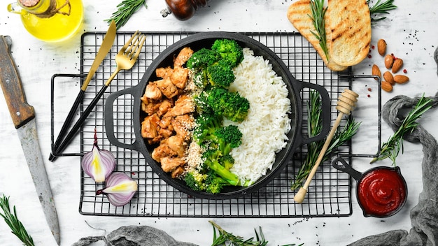 Healthy food Chicken with teriyaki sauce boiled rice and broccoli in a black pan Rustic style Top view