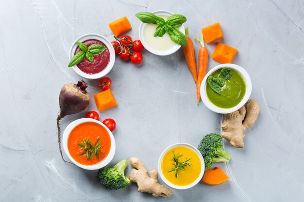 Healthy food, clean eating concept. Variety of colorful seasonal fall vegetables creamy soups with ingredients. Pumpkin, broccoli, carrot, beetroot, potato, tomato spinach. Flat lay, copy space