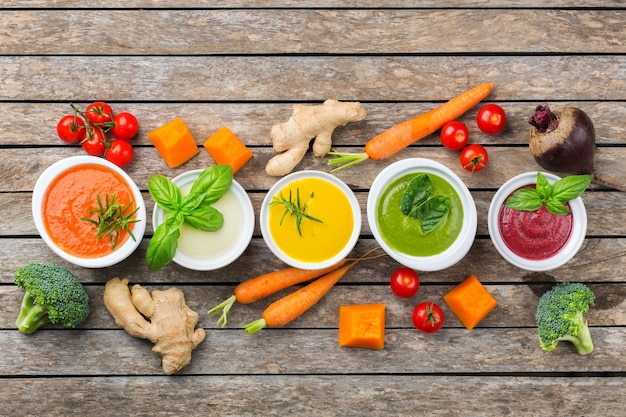 Cibo sano, concetto di mangiare pulito. varietà di zuppe cremose di verdure autunnali colorate di stagione con ingredienti. zucca, broccoli, carota, barbabietola, patata, pomodoro, spinaci. lay piatto