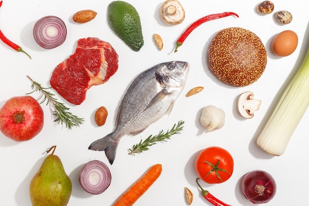 Healthy food clean eating selection: fruit, vegetable, seeds, fish, meat, leaf vegetable on white background. Top view.