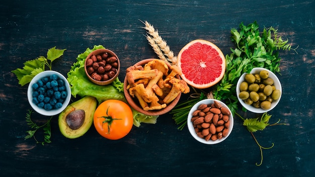 건강한 음식 깨끗한 식사 선택 야채 과일 견과류 열매와 버섯 파슬리 향신료 검정색 배경에 텍스트를 위한 여유 공간