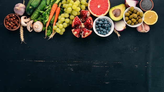 Cibo sano selezione di mangiare pulito verdure frutta noci bacche e funghi prezzemolo spezie su sfondo nero spazio libero per il testo