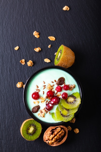 La ciotola variopinta della prima colazione del yogurt dell'alimento sano fruttifica guarnizione con lo spazio della copia