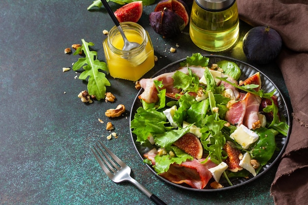 Healthy food concept Autumn salad with figs prosciutto arugula spinach cheese walnuts and honey