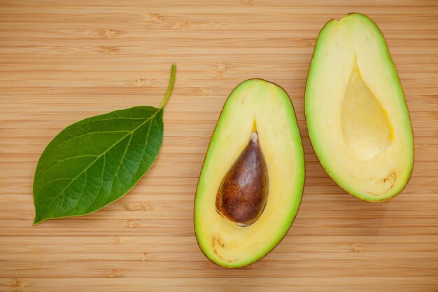 Healthy food concept Closeup ripe avocado with avocado leaves on wooden background Halved organic avocado with core on wooden background Top view with copy space