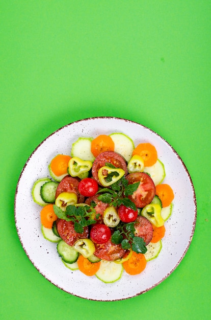Концепция здорового питания. pPlate с нарезанными свежими овощами на ярком фоне. Студийное фото.