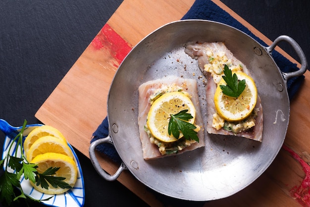 Cibo sano concetto di preparazione per il burro all'aglio limone fatto in casa merluzzo al forno pesce su sfondo nero con spazio per la copia