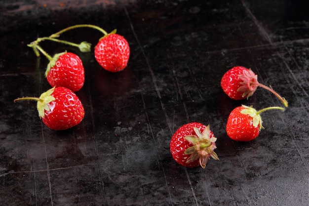 Healthy food concept Red juicy sweet strawberries with twigs on a black background Closeup of red berries